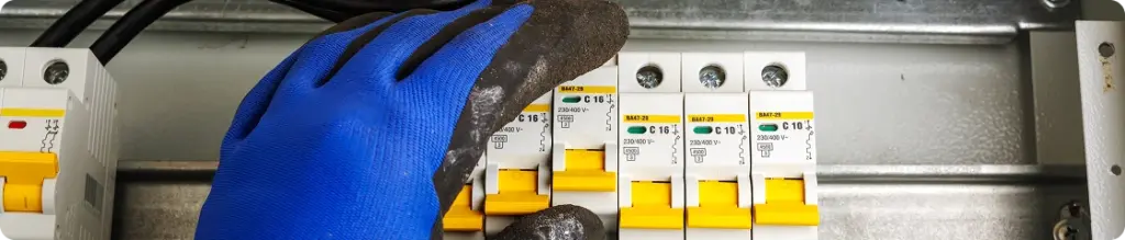 Elettricista che installa e regola gli interruttori automatici all'interno di un quadro elettrico residenziale.